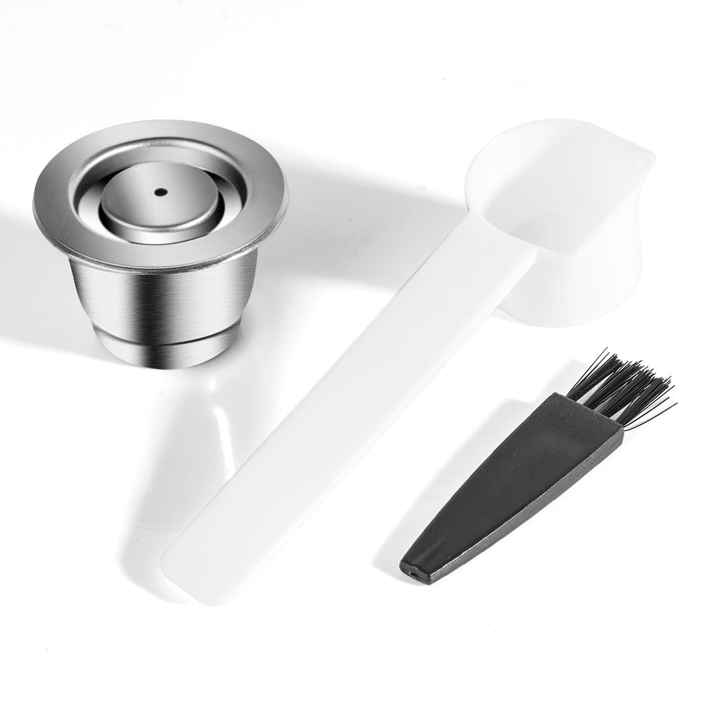 Single stainless steel coffee capsule. All on a white background. Includes a free brush and scoop.