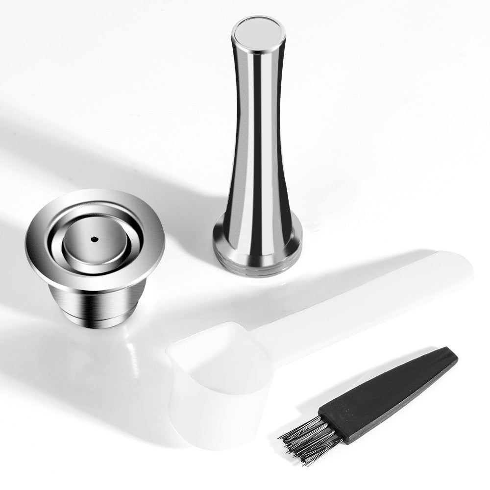 Stainless steel coffee capsule with accompanying tamper. All on a white background. Includes a free brush and scoop.
